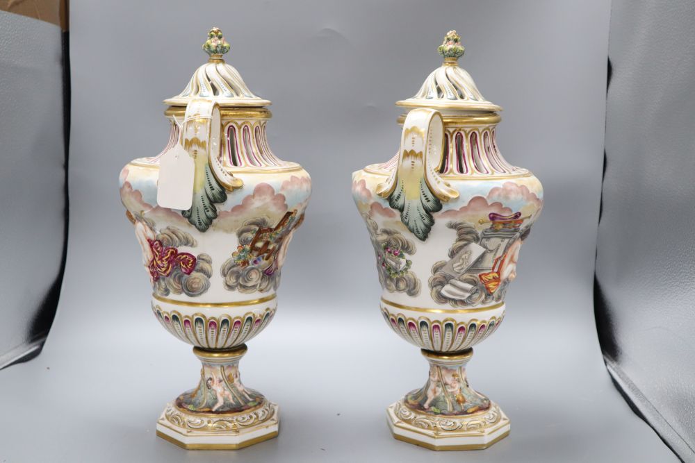 A pair of Ginori Doccia two handled lidded waisted baluster vases, in Capodimonte style moulded in relief with amorini, height 43cm
